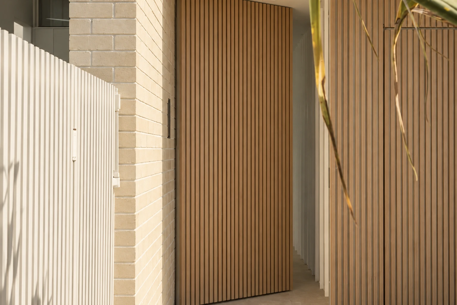 Knotwood supplier example: Wood-look batten pedestrian gate beside a masonry wall.